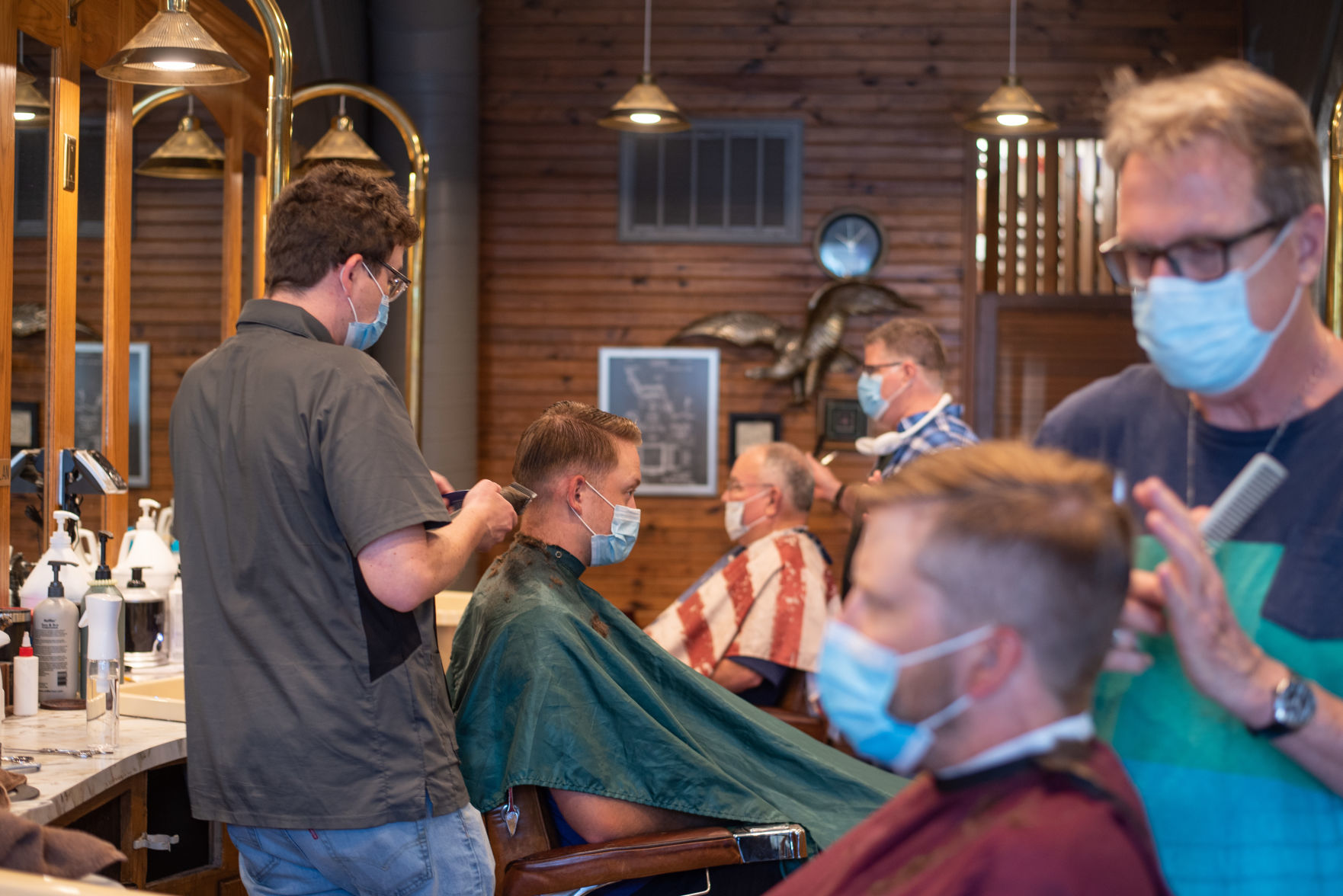 From the front, Randy Sievers cuts Adrian BakerÕs hair, Dylan Roberts cuts Jackson HermsÕ hair and Bryan Burrows cuts Jim Pitts hair at Campus Barbershop on Wednesday.